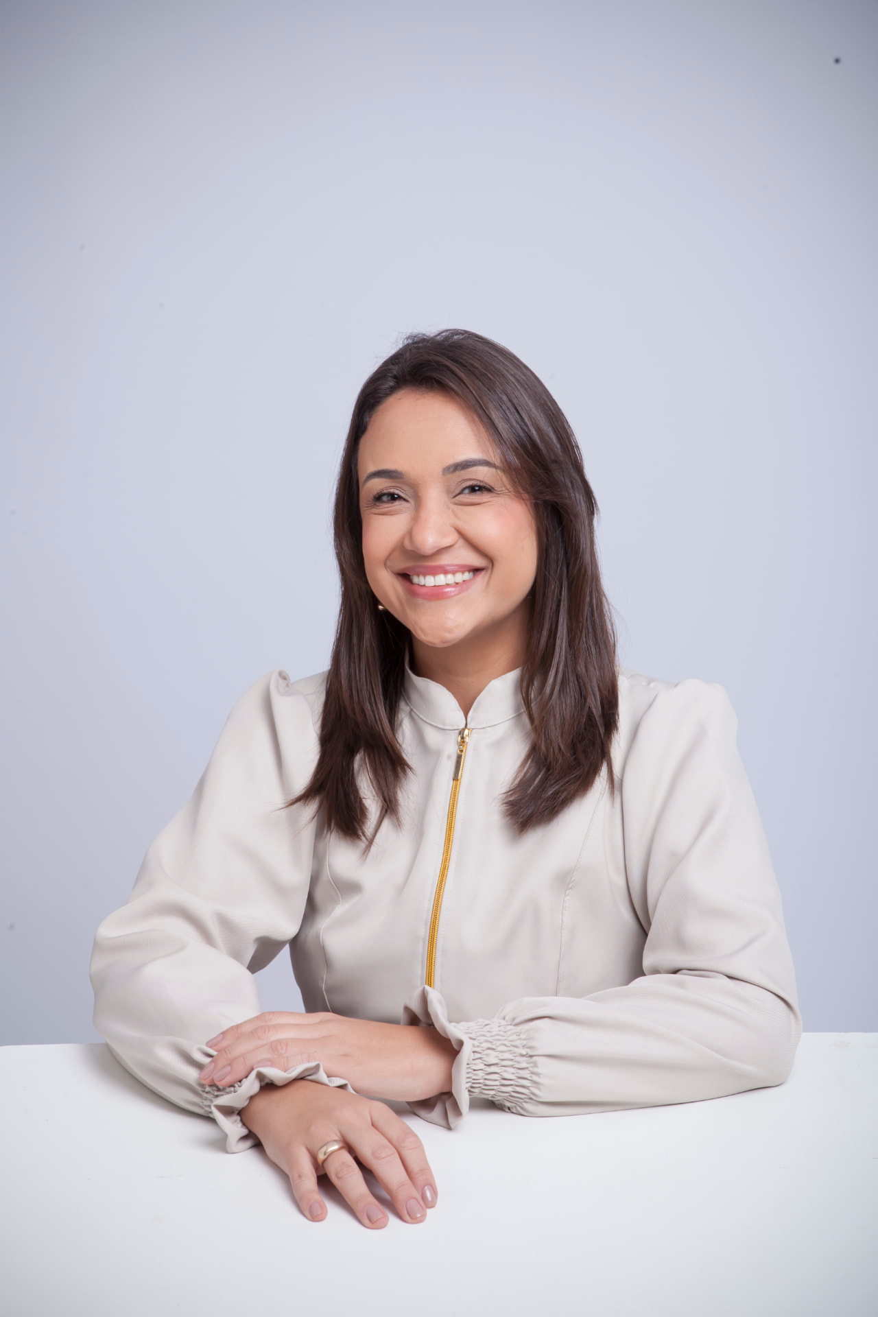 Cíntia Lemos sorrindo em ambiente clínico, com jaleco claro